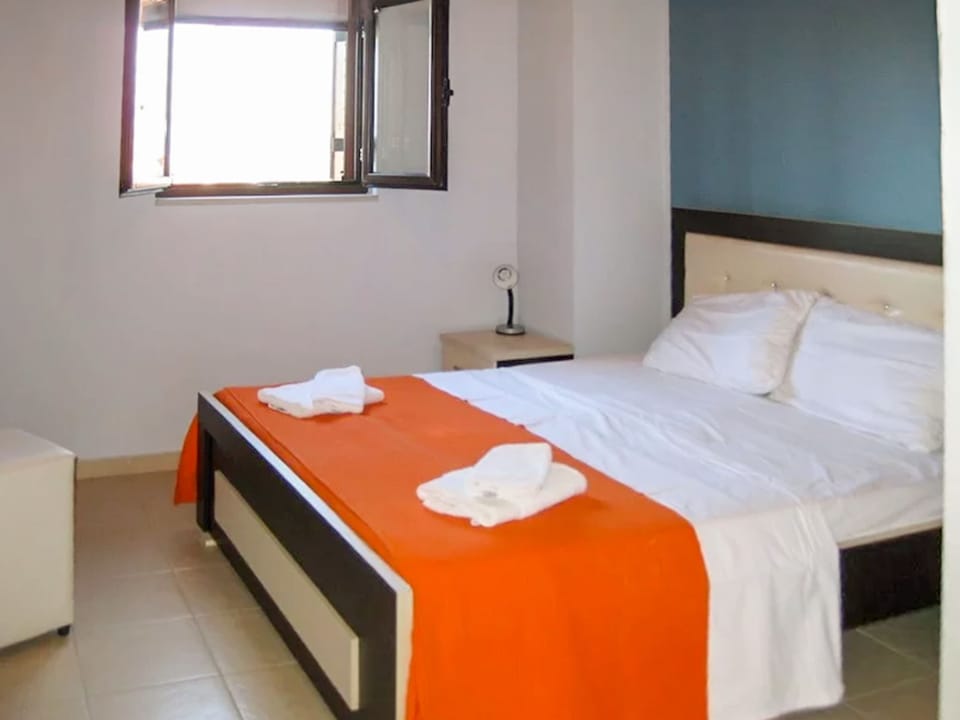 Bright and inviting bedroom with a comfortable double bed and natural light from the open window