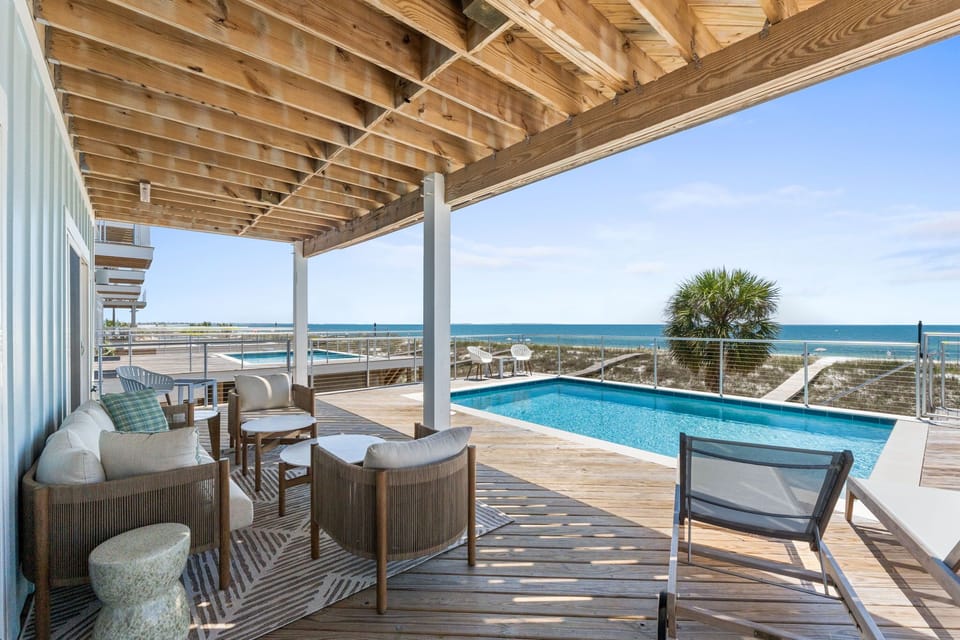Relax under the pergola while gazing at turquoise waters and pristine beaches just beyond your private pool—coastal living at its finest.