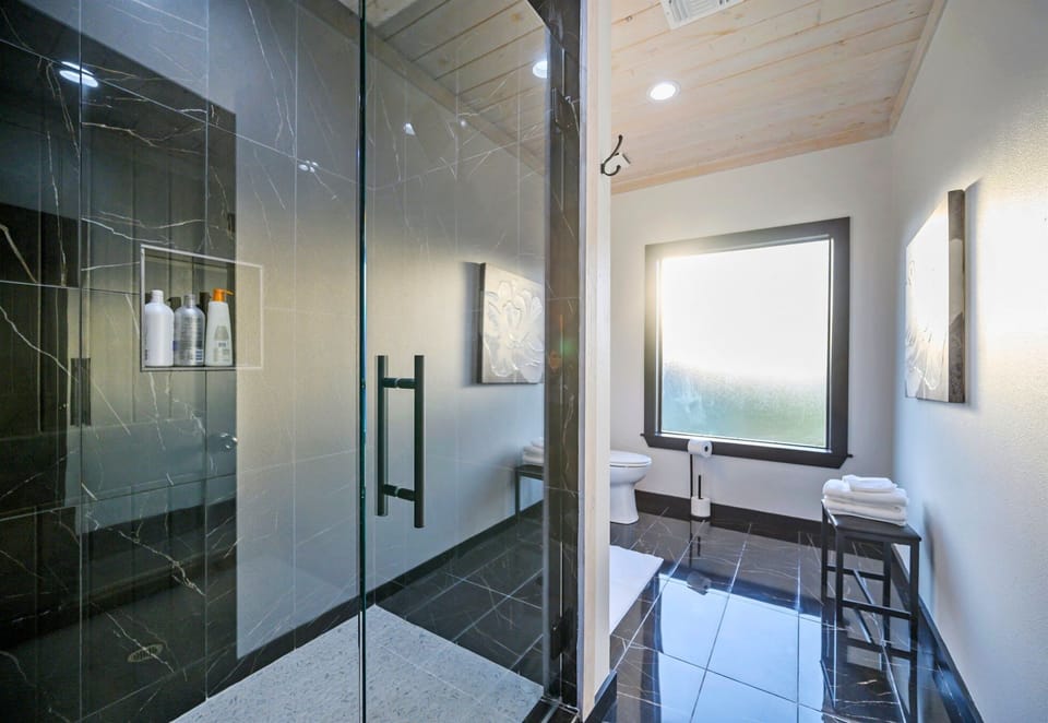 Refresh and recharge in the walk-in shower surrounded by rich textures, glass, and stylish modern tile.