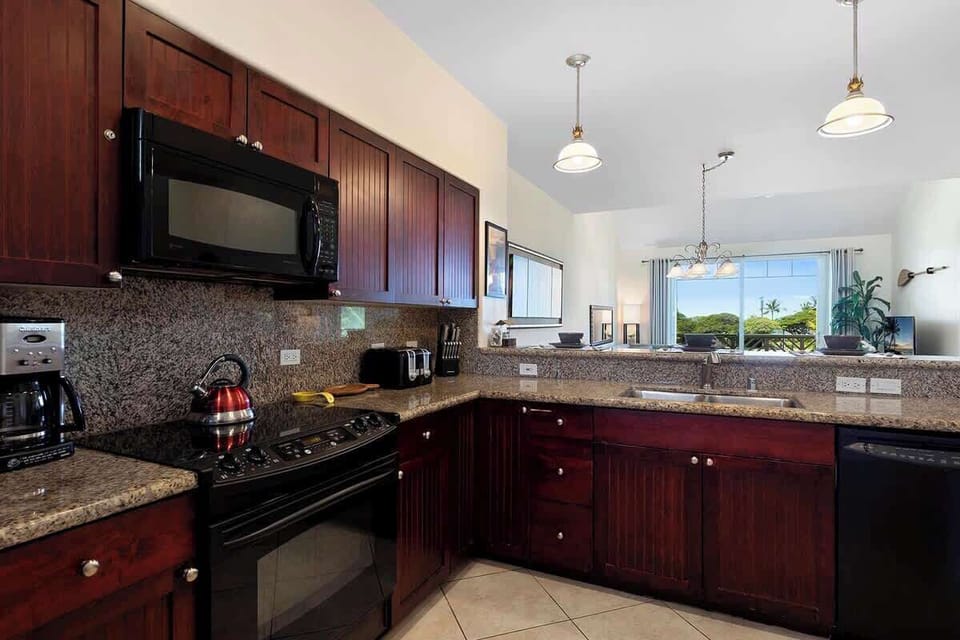 - Dark wood cabinets and granite counters
- Modern appliances & pendant lights
- Open view into dining and living space