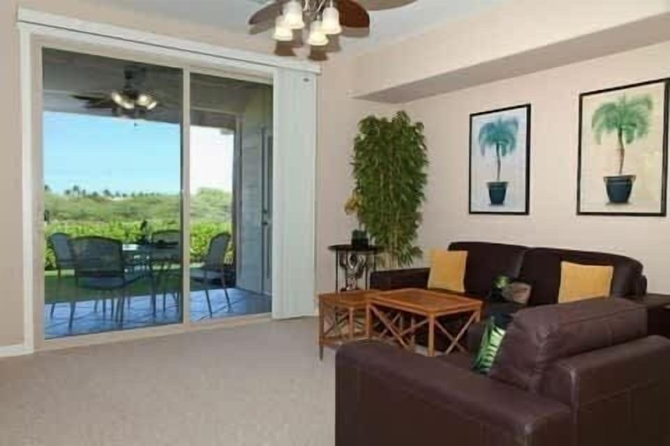 Relax in this comfy lounge area that opens to a breezy lanai with beautiful greenery beyond.