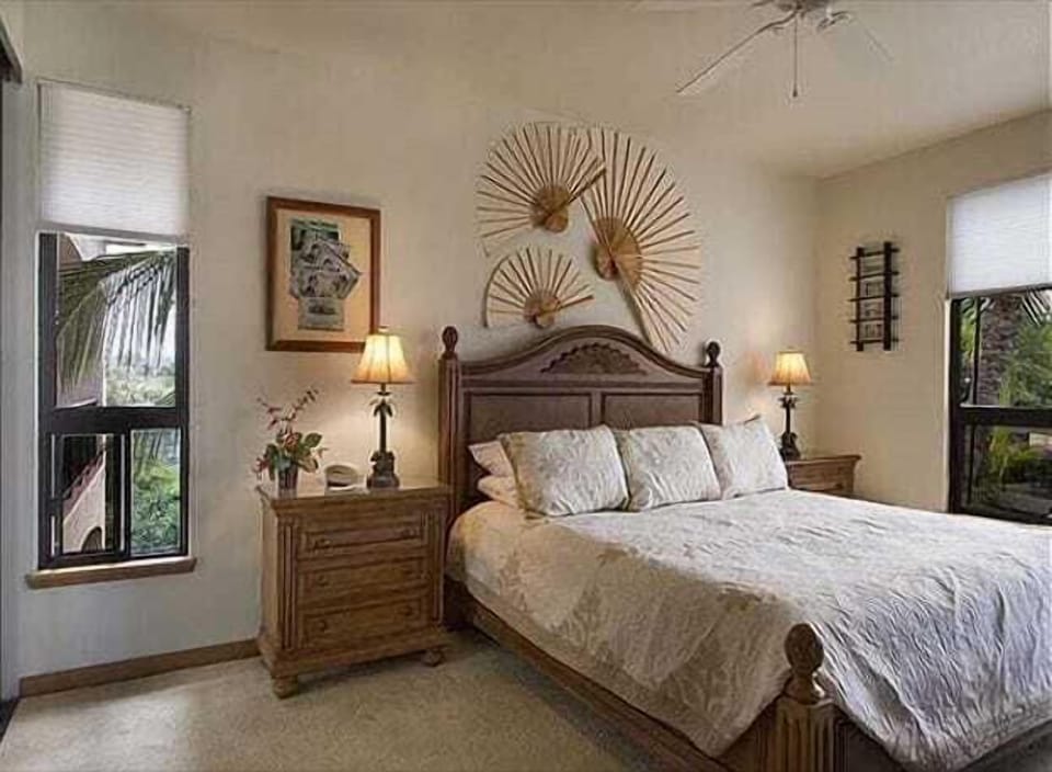 Relax in this serene bedroom featuring a tropical-theme decor and a view of lush greenery from the window.