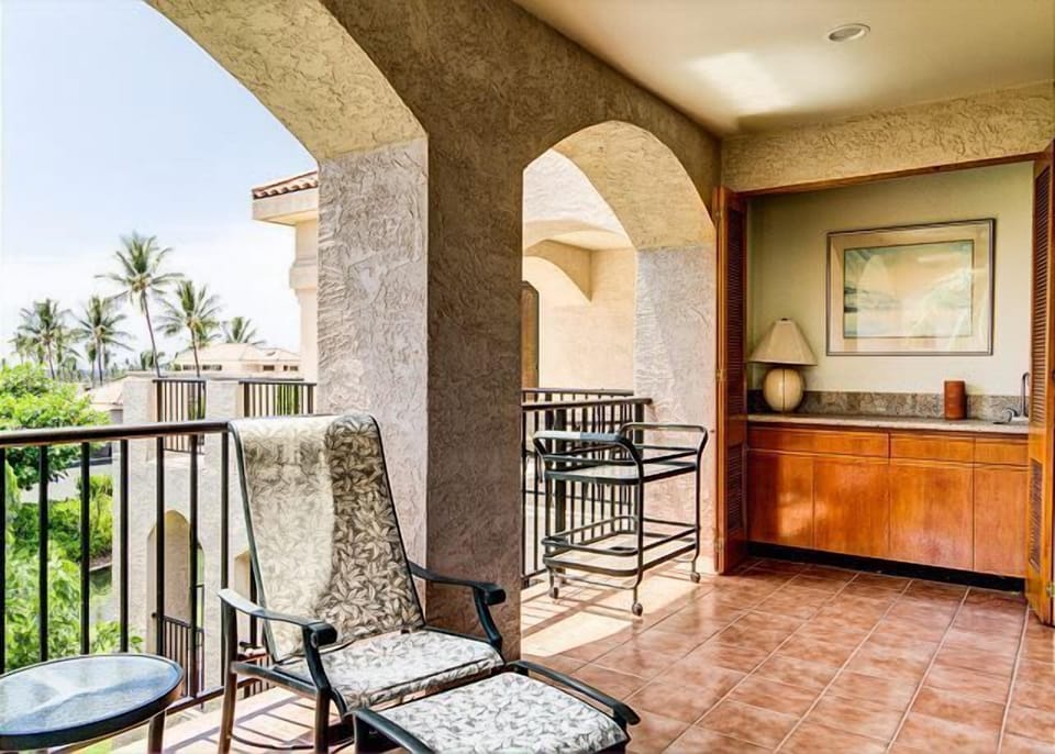 Relaxing balcony with comfortable seating and a built-in wet bar, overlooking tropical scenery.