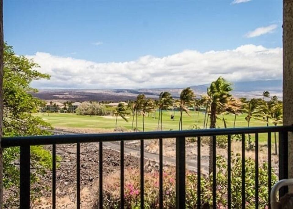 Breathtaking golf course views from your private balcony, with distant mountains and tropical trees.