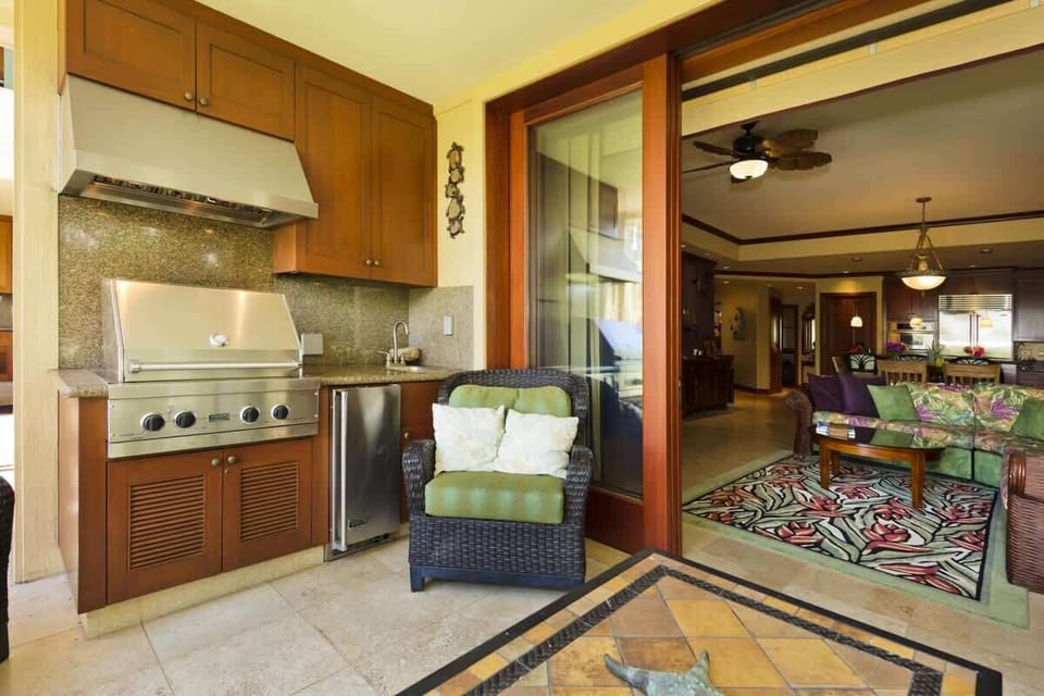 Lanai grill station with stainless barbecue, granite counters, and comfy seating flows inside too.

