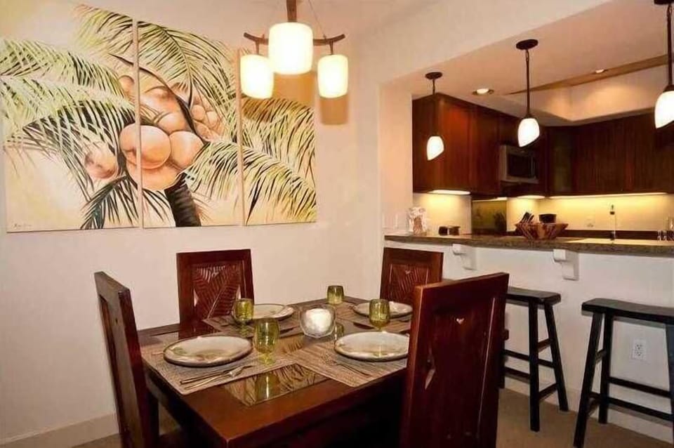 Gather for meals under warm pendant lights and palm inspired art, with bar seating at the kitchen.

