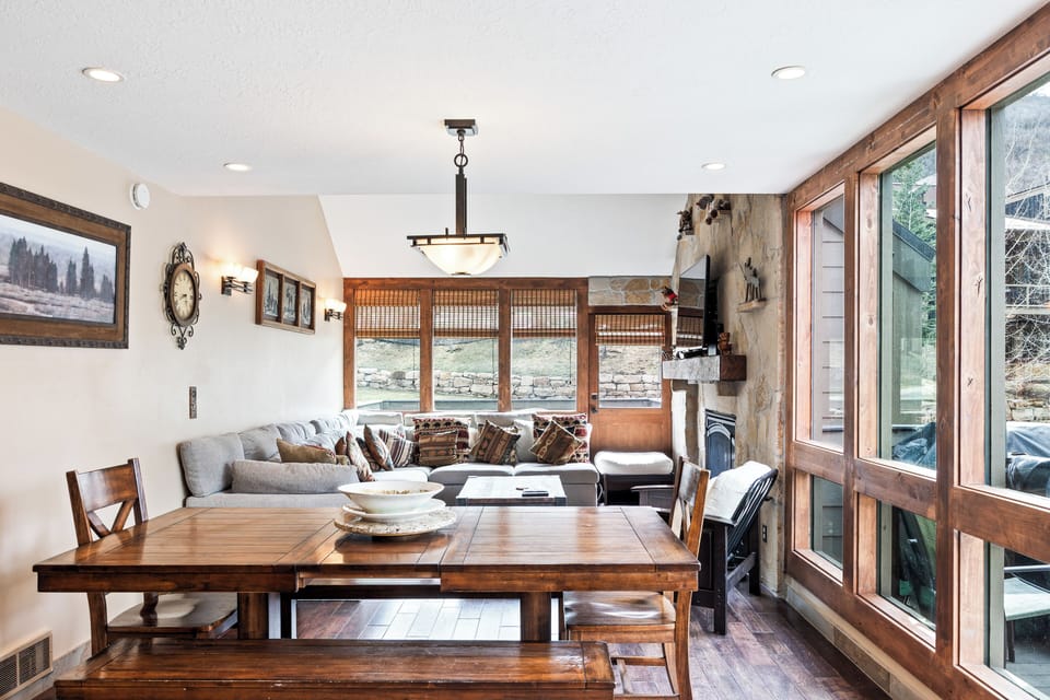 - Rustic dining area with bench seating perfect for group meals  
- Cozy living space features sectional sofa and stone fireplace  
- Large windows bring in light and mountain scenery all around