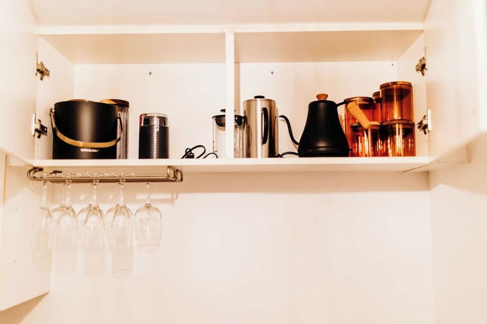 Fully stocked kitchen includes a champagne bucket, coffee grinder, milk frother, French press, electric tea kettle, and hanging wine glasses—perfectly equipped for slow mornings or festive evenings.



