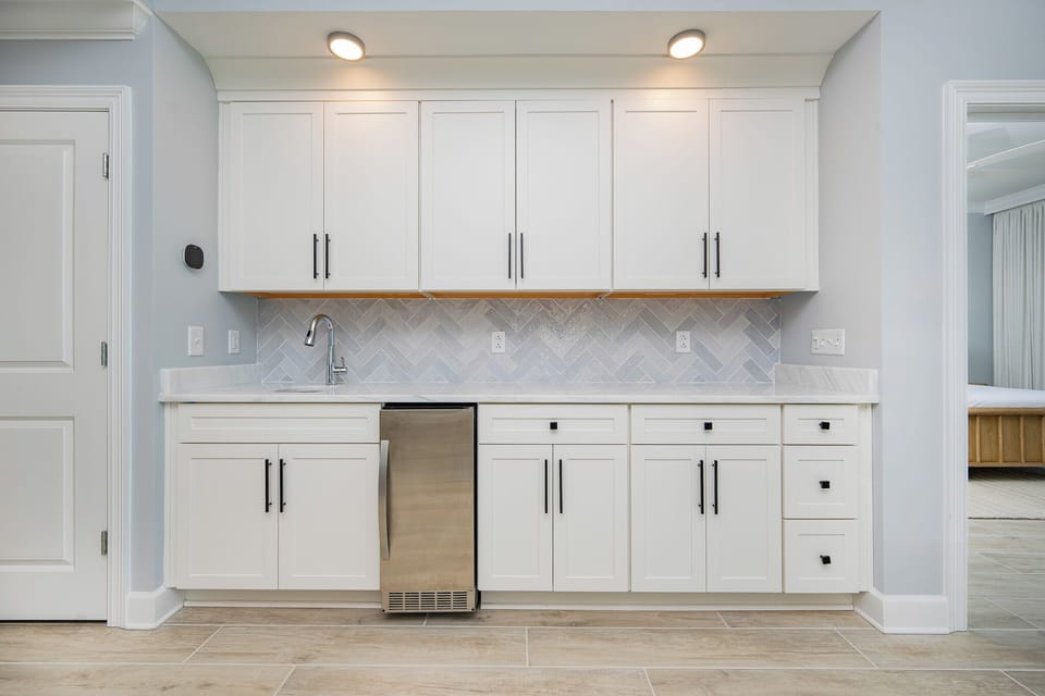 Prepare snacks and drinks in the sleek wet bar featuring stylish cabinetry and tile accents