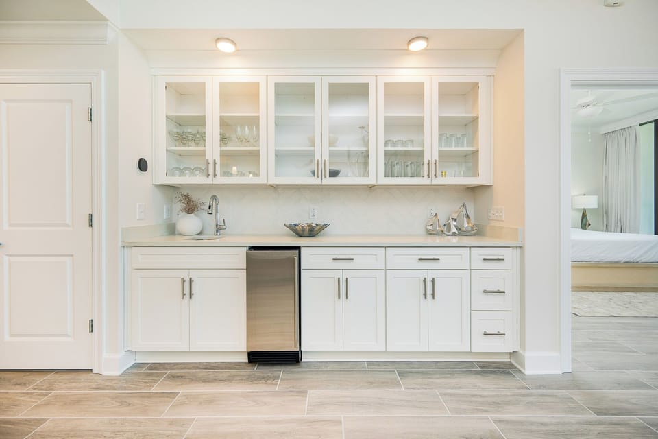 Enjoy preparing drinks and snacks at the wet bar with sleek cabinetry and elegant glassware displays