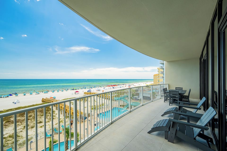 Relax on your beachfront balcony, enjoying views of the coast, vibrant umbrellas, and pool area below
