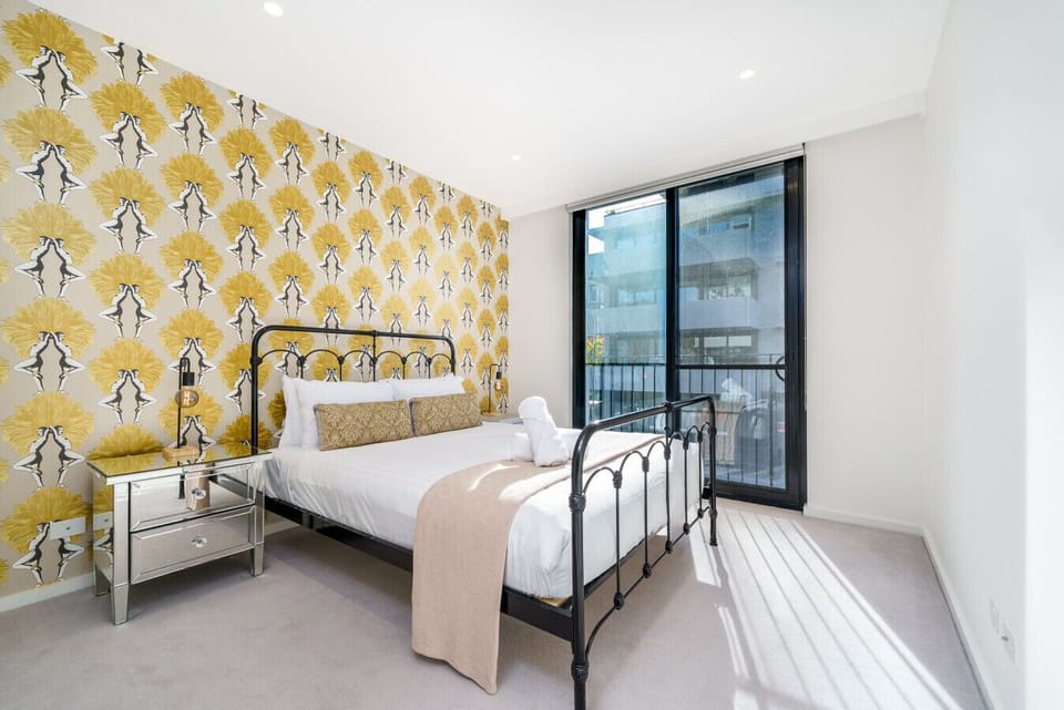 A spacious bedroom with vibrant African-inspired wallpaper and a comfortable queen bed.