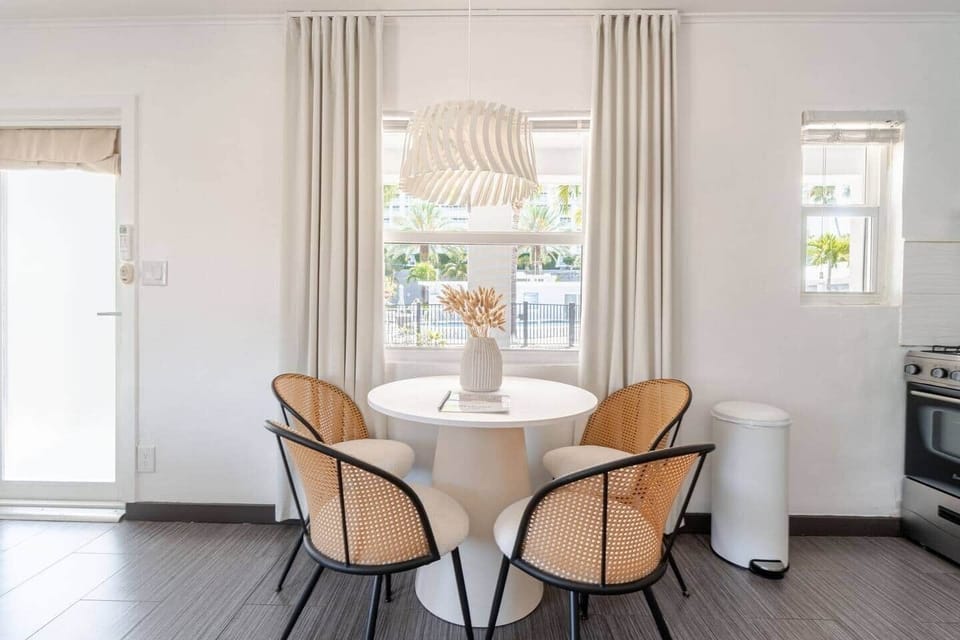 Light-filled dining area with views of the pool, featuring a round modern table and four chairs—perfect for comfortable, relaxing meals or working while enjoying the peaceful poolside scenery.