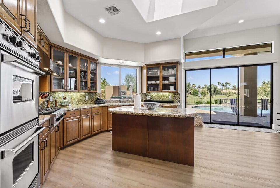 Spacious kitchen w/ central island, rich cabinetry & wide sliding doors to the patio