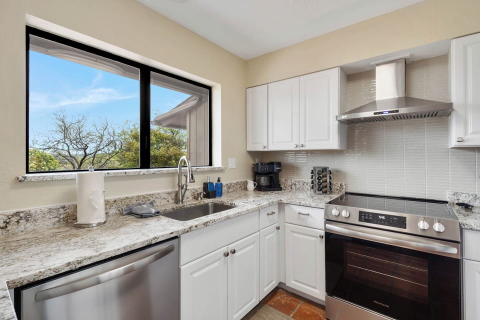 Bright kitchen, fully stocked, stainless steel, terracotta tile.