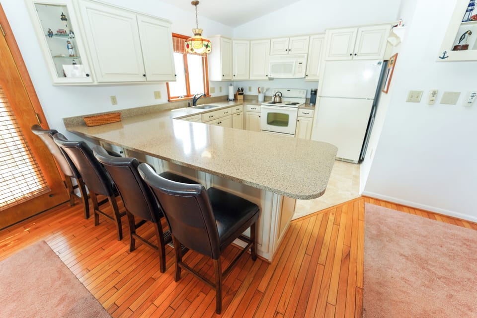 50 S. Anchorage - Kitchen Peninsula - Modern kitchen featuring a granite-topped breakfast bar with high-back leather stool seating, ideal for casual dining and entertaining.