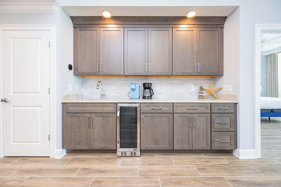 Prepare your favorite beverages with ease at the stylish wet bar featuring a coffee corner and wine cooler