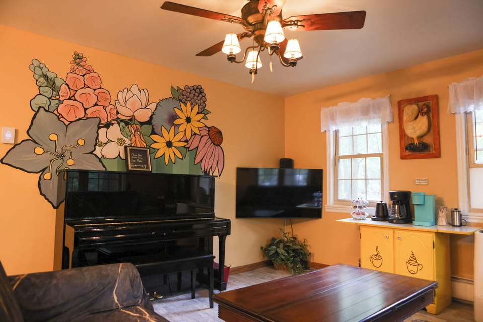 Living room with Yamaha piano and large Smart TV and well stocked coffee station.