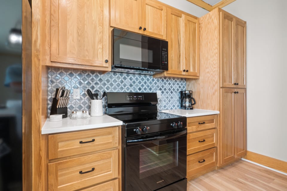 Your fully-equipped kitchen features warm oak cabinets, stylish tile backsplash, and modern appliances for all your culinary adventures.