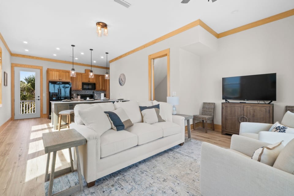 Sink into plush white sofas in your open-concept living space, where natural light streams through and modern amenities await your perfect getaway.