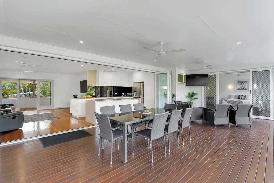 The expansive deck seamlessly connects indoor and outdoor living, featuring multiple seating areas and a dining set ideal for entertaining or relaxing in the fresh air.