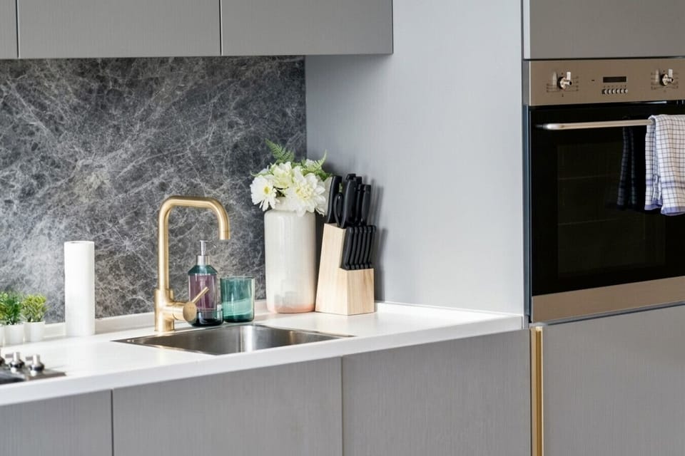 Fully equipped kitchen with a marble splashback, brass tapware, and a built-in oven. A full knife block, gas cooktop, and clean white benchtops make home-cooked meals easy during your stay.