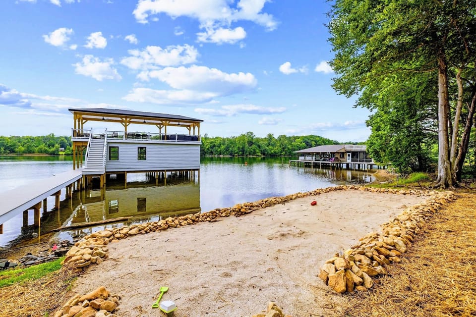 Beach - The private sandy beach curves along the shoreline, boathouse to one side and open water ahead.
