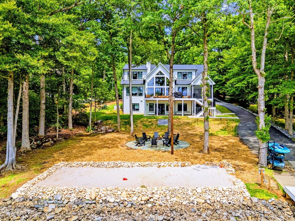 Aerial - A straight-on look at the rear of the house, fire pit patio and sandy beach below.