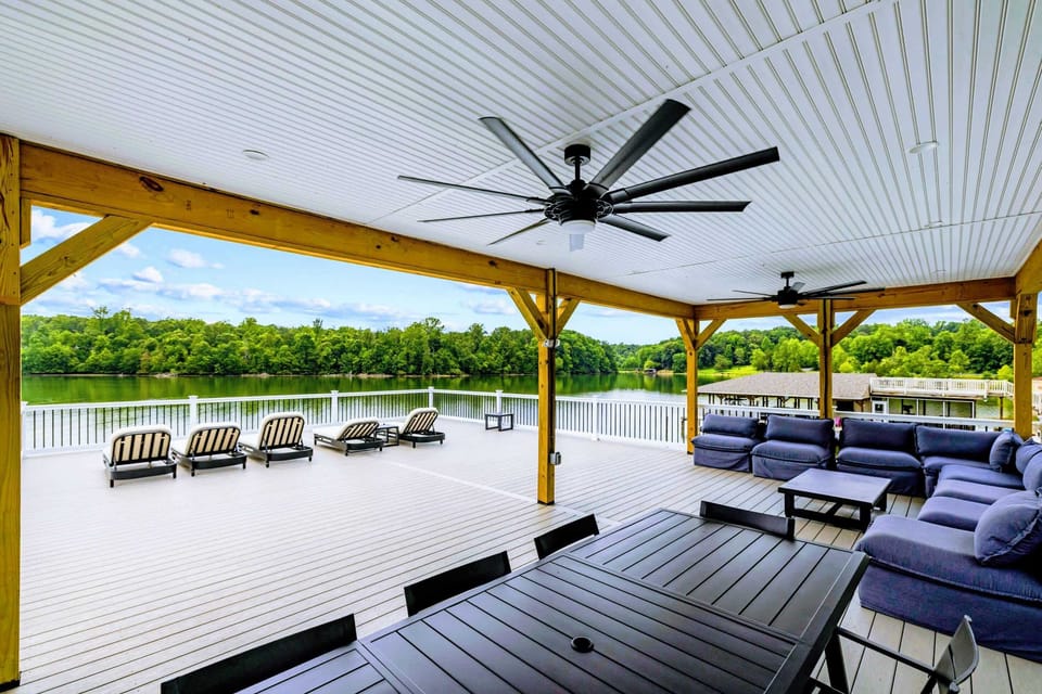 Boathouse Deck - The covered upper deck pairs loungers, a dining table, and a sectional under big ceiling fans, lake on every side.