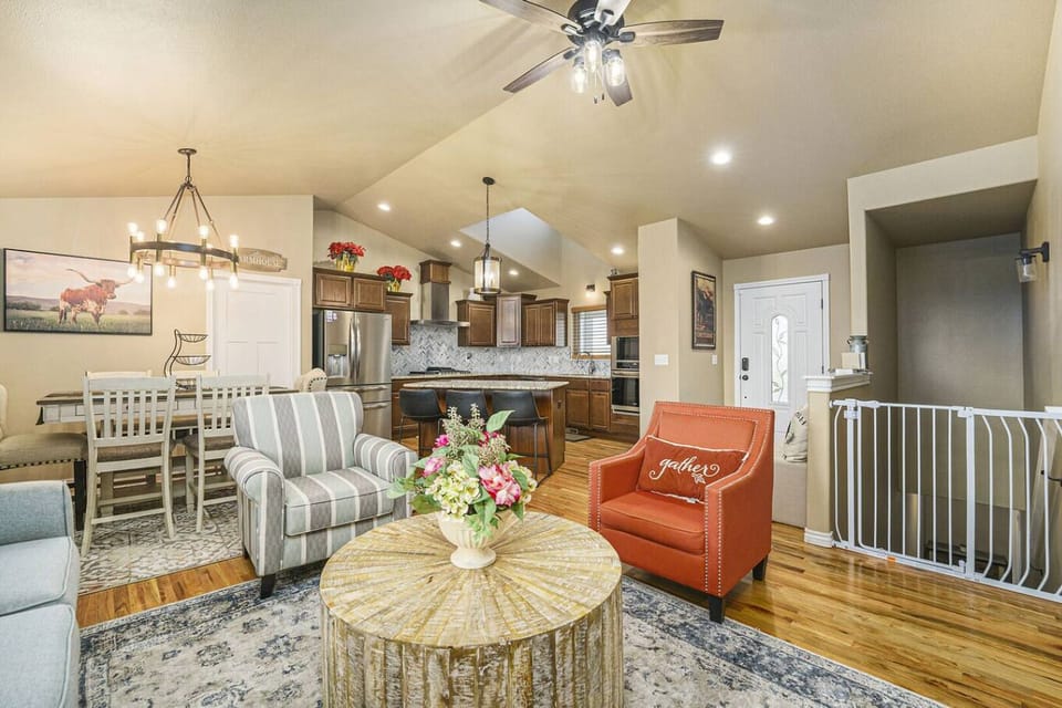 - Open concept living area blends rustic charm with cozy farmhouse flair and vibrant accents
- Stylish armchairs and a pop of color from the red chair invite conversation
- Kitchen and dining nearby make hosting easy and enjoyable

