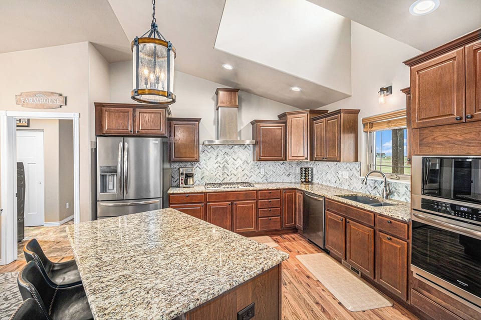 - Spacious kitchen with granite countertops, wood cabinetry, and stainless steel appliances
- Large center island offers extra prep space and casual seating for guests
- Skylight and tile backsplash bring light and texture into this chef’s haven