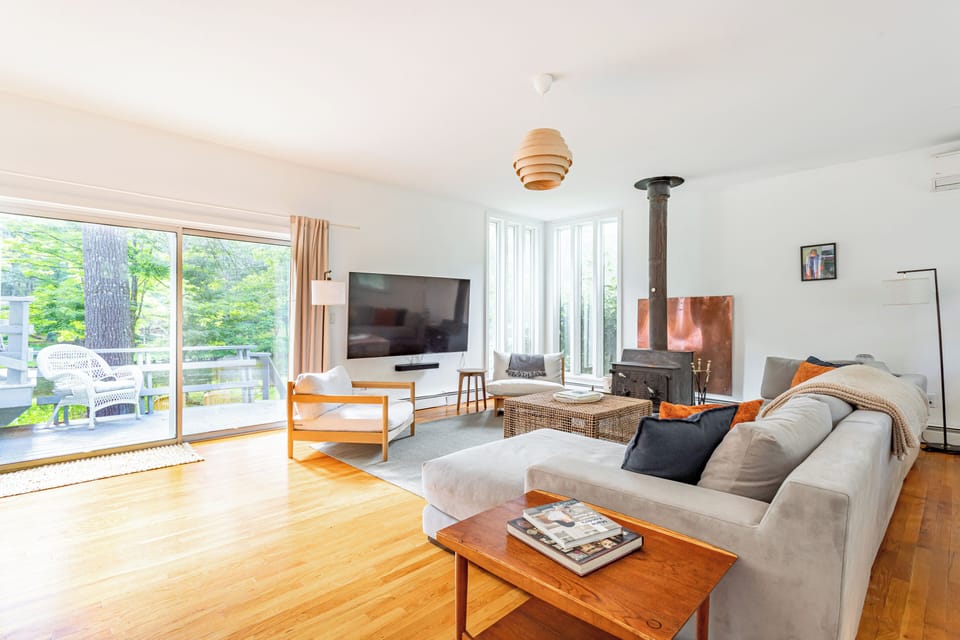 Spacious, comfortable living room with a cozy fireplace and large windows that fill the space with natural light and stunning views of the outdoors.