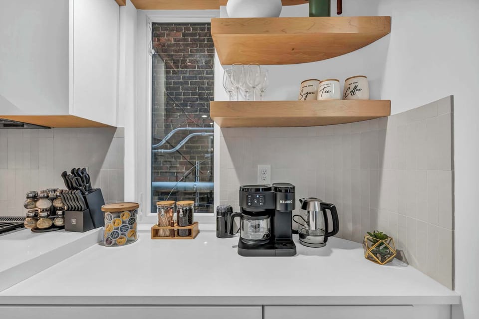 A stylish kitchen nook complete with a coffee maker, electric kettle, and neatly arranged shelves, providing the perfect space for your morning routine.
