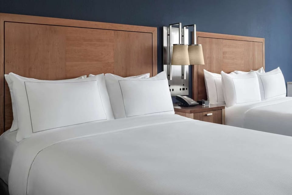 Cozy queen beds with soft white linens and wooden headboards