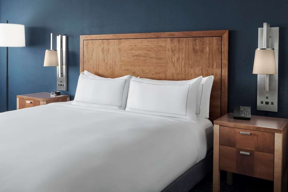 Room with king bed, soft white bedding, and wooden headboard