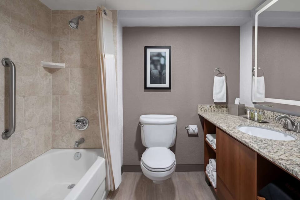Bathroom with bathtub, granite counter, and fresh towels ready