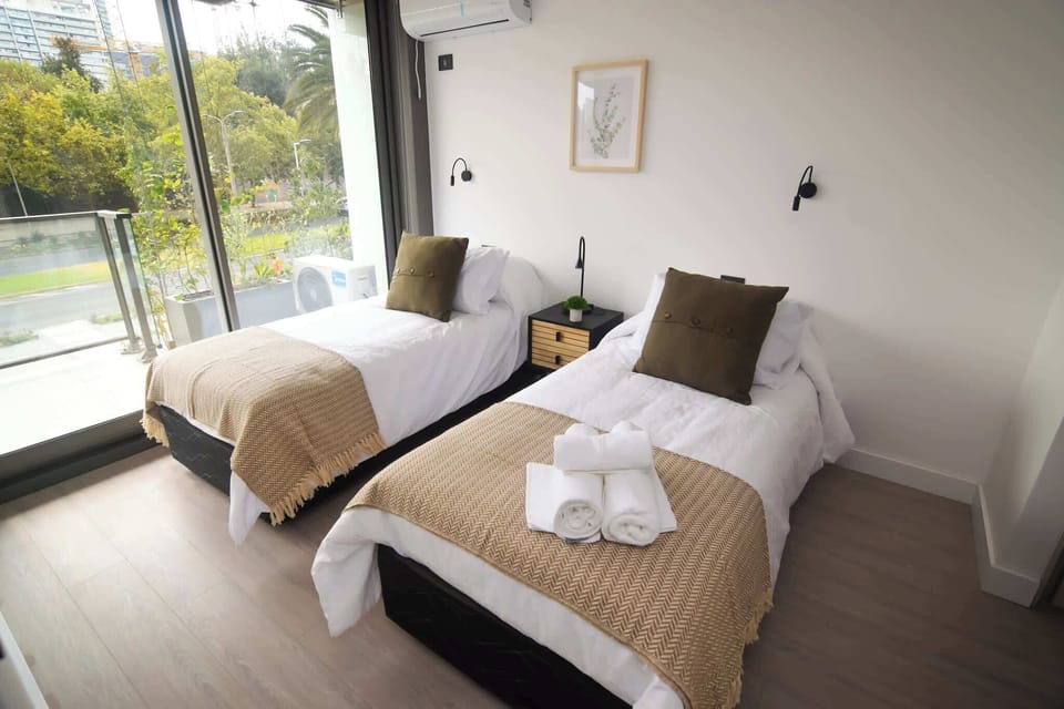 Cozy twin bedroom with large windows offering serene views, perfect for a relaxing stay.