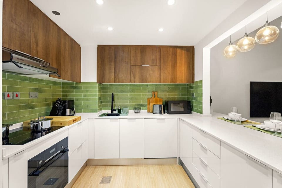 Kitchen Delight: Modern kitchen with vibrant green tiles, sleek appliances, and ample cooking space!