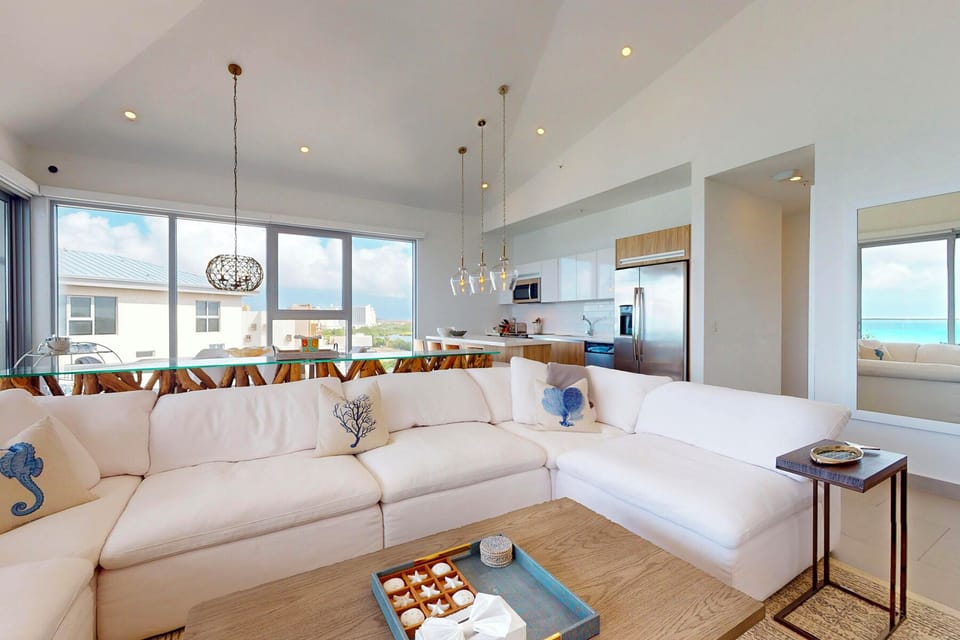 Sink into plush white sofas and enjoy open-concept living with stunning sea views just beyond your windows, where modern island style meets effortless relaxation.