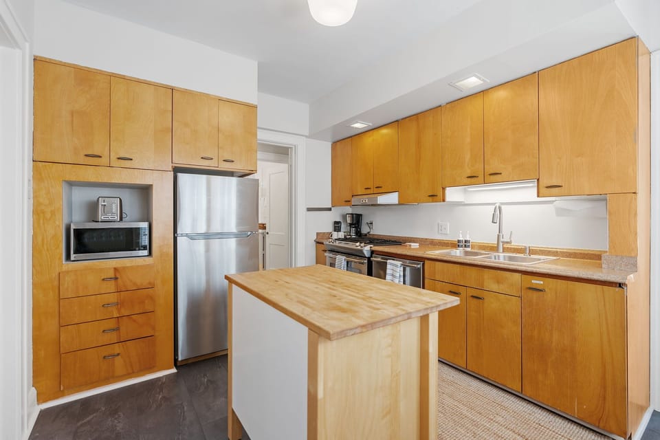 Your fully equipped kitchen features warm wood cabinetry, stainless appliances, and a convenient island perfect for meal prep and morning coffee.