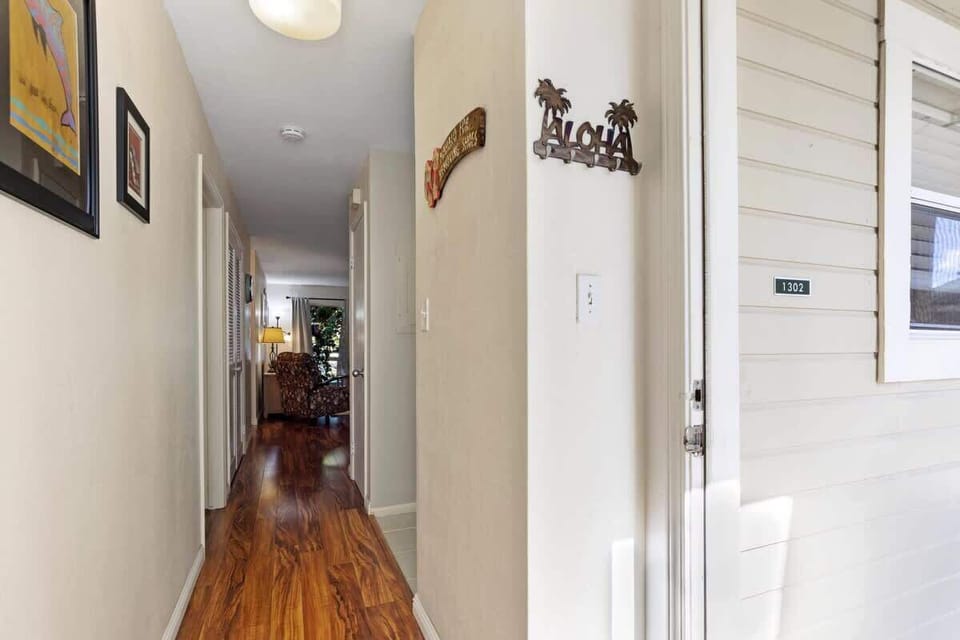 Step into a warm “Aloha” welcome with sleek wooden floors guiding you through a well lit hallway.