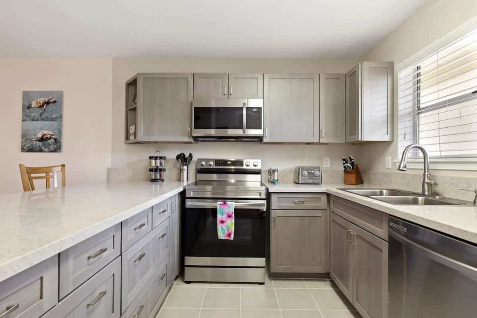 Enjoy cooking in a fully equipped modern kitchen with stainless steel appliances, stone counters, and natural light.