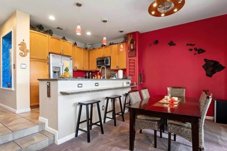 Vibrant kitchen with a red accent wall, bar seating, and a cozy dining area, perfect for enjoying homemade meals.
