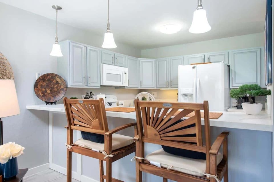 White quartz breakfast bar with stylish barstools and soft cabinetry adds charm to full kitchen.

