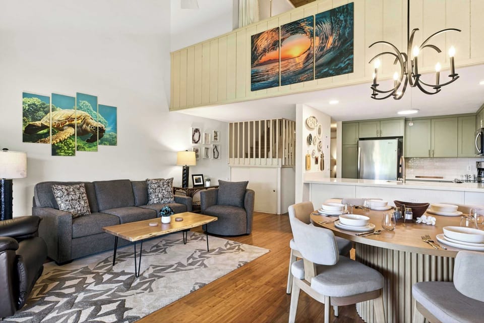 Bright open concept living and dining with beachy decor, plush sofas, and easy kitchen access.