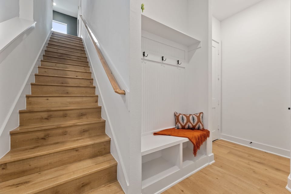 Welcoming Entryway with Coat Hooks and Stylish Staircase

