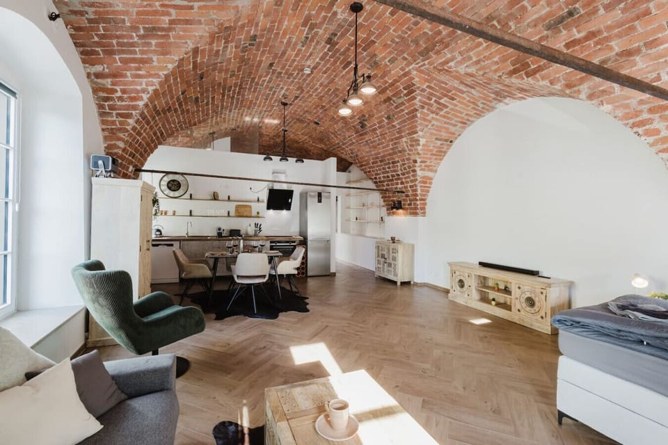 Airy open-concept living and dining space with exposed brick and modern kitchen.