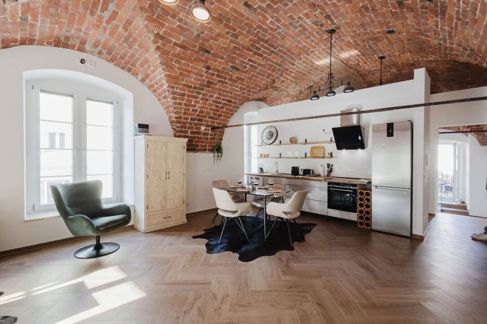 Bright and airy open-concept space with seating area and a fully equipped kitchen beneath original brickwork.