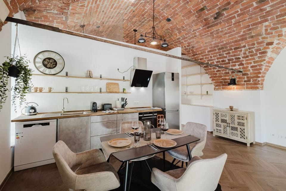 Fully equipped modern kitchen with dining area set under stunning exposed brick ceilings — perfect for family meals or romantic dinners.
