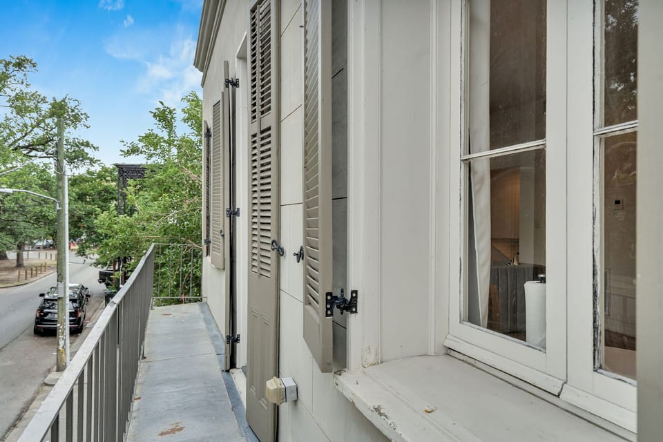 Charming balcony with classic shutters—perfect for a quiet moment overlooking a peaceful New Orleans street.